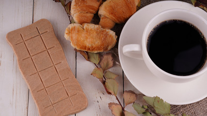 A hot cup of coffee with a bar of chocolate on the table in a cafe. Composition of a delicious coffee and sweet snack.