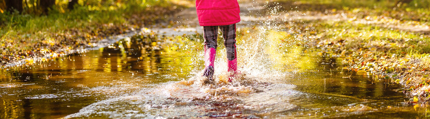 Playful little girl hiding behind colorful umbrella outdoors