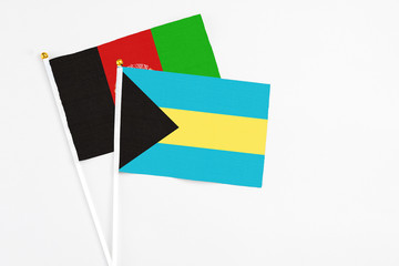 Bahamas and Afghanistan stick flags on white background. High quality fabric, miniature national flag. Peaceful global concept.White floor for copy space.