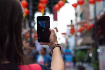 Unrecognizable woman takes a selfie with a smartphone  at chinatown