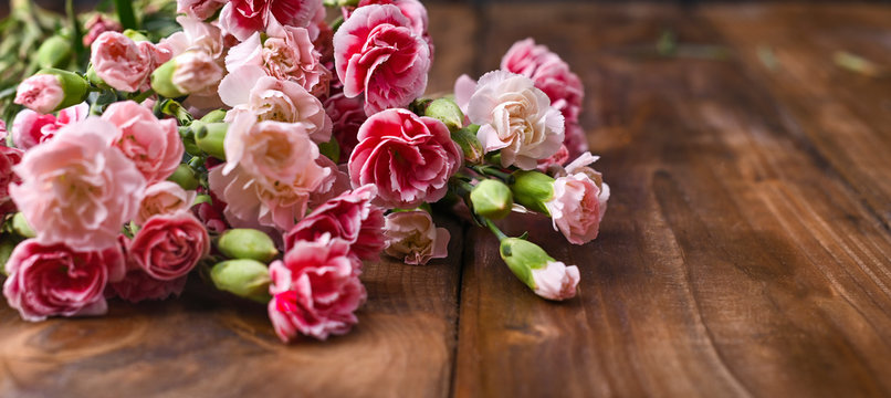 Carnation with pink and white petals on a wooden table. A bouquet of flowers as a gift. Vintage photo. Free space for text.