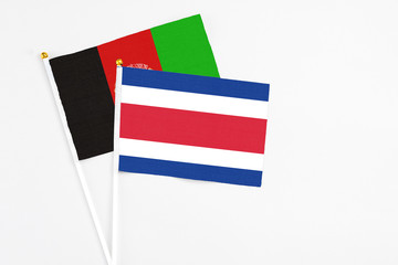 Costa Rica and Afghanistan stick flags on white background. High quality fabric, miniature national flag. Peaceful global concept.White floor for copy space.
