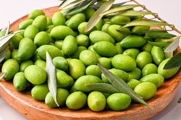 Fresh green olives with branches and leaves. Seasonal harvest in Italy. Top view.