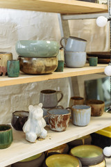 Ceramic bear and handmade dishes on the shelf of the pottery workshop.