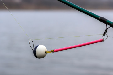 spinning bite indicator, a nod on a fishing rod by the river