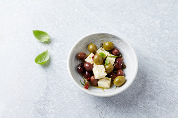 Green and kalamata olives, capers and feta cheese on bright stone background. Healthy Snack Idea. Close up. Copy space. 