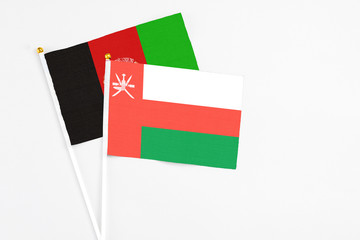 Oman and Afghanistan stick flags on white background. High quality fabric, miniature national flag. Peaceful global concept.White floor for copy space.