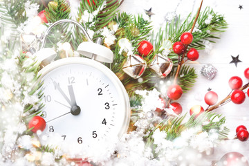 Christmas clock, fir branches and berries covered snow. New Year greeting card.