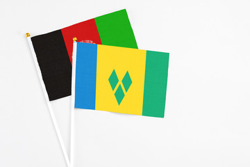Saint Vincent And The Grenadines and Afghanistan stick flags on white background. High quality fabric, miniature national flag. Peaceful global concept.White floor for copy space.