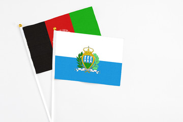 San Marino and Afghanistan stick flags on white background. High quality fabric, miniature national flag. Peaceful global concept.White floor for copy space.