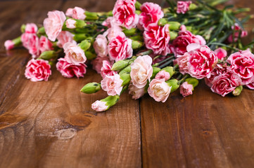 Carnation with pink and white petals on a wooden table. A bouquet of flowers as a gift. Vintage photo. Free space for text