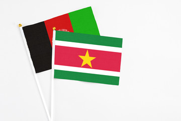 Suriname and Afghanistan stick flags on white background. High quality fabric, miniature national flag. Peaceful global concept.White floor for copy space.