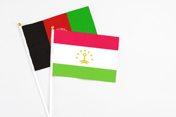 Tajikistan and Afghanistan stick flags on white background. High quality fabric, miniature national flag. Peaceful global concept.White floor for copy space.