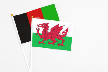 Wales and Afghanistan stick flags on white background. High quality fabric, miniature national flag. Peaceful global concept.White floor for copy space.