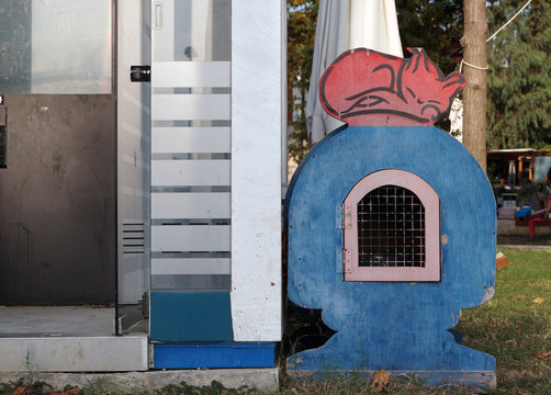 A wooden house with lattice door for homeless cats of blue color stands on a city street. The need to care for stray animals. The symbolic image of a sleeping cat.