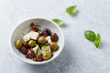 Green and kalamata olives, capers and feta cheese on bright stone background. Healthy Snack Idea. Close up. Copy space. 