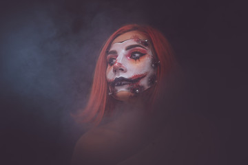 Attractive girl is playing role of creepy dead doll in misty smoke.