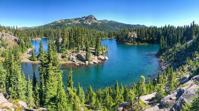 A high elevation volcanic mountain lake surrounded by hills and green trees.