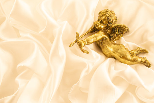 small gold kupidon on  cream background