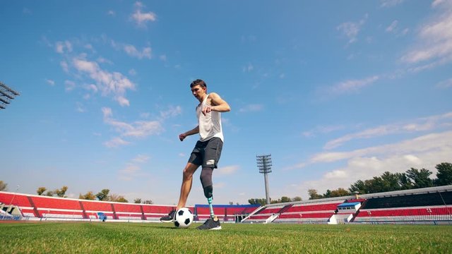 A man with an artificial leg is dribbling a ball in slow motion