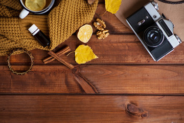 The concept of a cozy retro photo in autumn style, a sweater, a retro camera, a night light wooden star, vintage, a mug with hot tea, lemon and cinnamon, aroma oil in a cozy house. Against the backgro