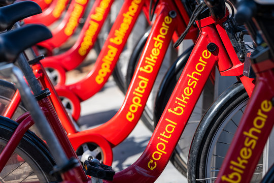 Washington DC, USA - April 5, 2018: Closeup of many parked bike rent, rental parking at docking station near road from capital bikeshare red bicycles row on sidewalk street in capital city