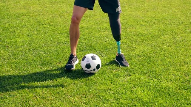 A man with a bionic leg is dribbling the ball at the green lawn