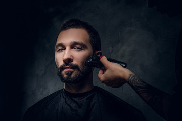 Portrait of pensive man with receive moustache and beard trimming procedure at barbershop.