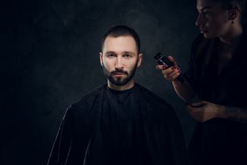 Concept of barbershop - elegant man gets a hair trimming from female hairdresser.