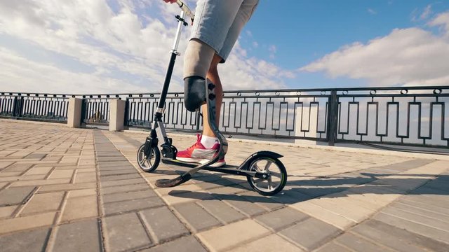 Slow motion of a man with prosthetic leg riding a scooter
