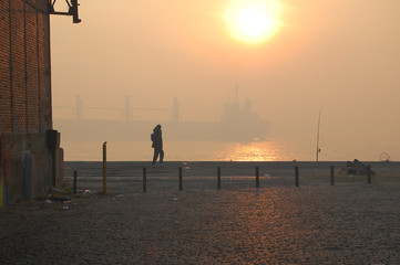 Plakat silhouette of people walking on pier at sunset