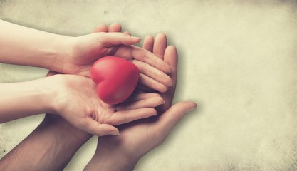 adult and child hands holiding red heart, heart health and donation concept