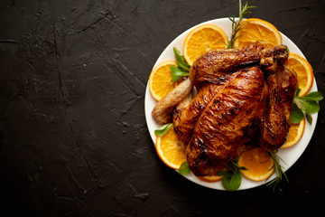 Roasted whole chicken or turkey served in white ceramic plate with oranges