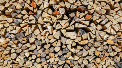 A close-up stock dry pile of chopped firewood timber laid in a woodpile stack