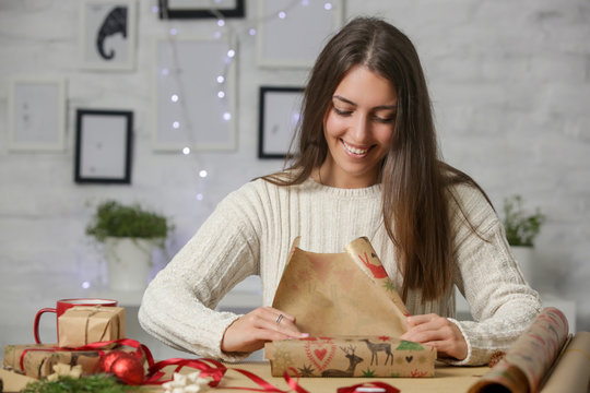 Happy smiling woman wrapping Christmas presents, winter holidays, gifting season concept