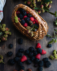 Ripe fresh raspberries and blackberries with straw basket
