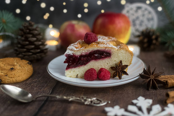 Delicious Christmas raspberry pie with berry filling and icing sugar and spices on a dark background.