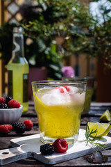 Cold refreshing tarragon, blackberry and raspberry lemonade with ice on wooden rustic table i