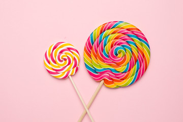Colorful lolipops spiral with wooden stick on pink background , childhood sweets