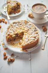 Whole delicious apple cake with almonds served on wooden table