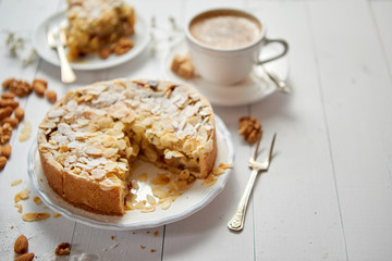 Whole delicious apple cake with almonds served on wooden table