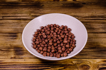 Ceramic plate with chocolate cereal balls on wooden table