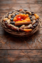 Mix of dried fruits in a small wicker basket on wooden table