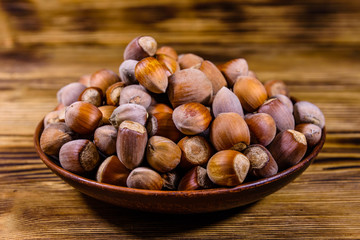 Plate with pile of hazelnuts on a wooden table