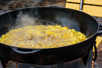 Heap of the french fries preparing in a big cauldron