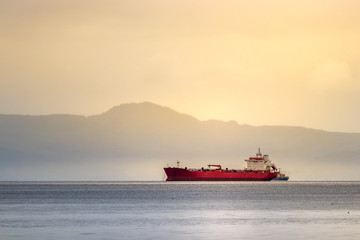A red tanker ship sailing at high seas in the Bering sea at sunset.