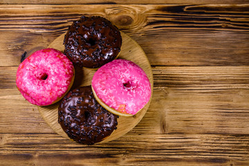 Cutting board with glazed donuts on a wooden table. Top view