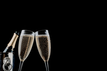 Christmas and New Years eve celebration concept: two glasses full of bubbly drink and a bottle of champagne on a table with Christmas decorations.