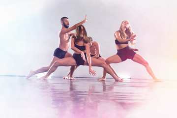 Fototapeta premium Young modern dancers dancing in the studio. Sport, dancing and urban culture concept. Group of young dancers performing on the stage. Effective performance. beautiful dance.