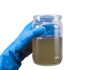 dirty contaminated infectious water in a jar in hand rubber glove isolated on white background